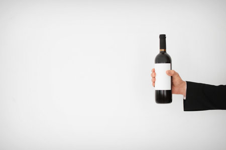 Man holding bottle of wine on light backgroundの写真素材