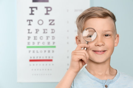 Cute little boy with magnifier in ophthalmologist officeの写真素材