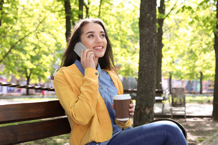 Young woman talking by phone outdoors on sunny dayの写真素材