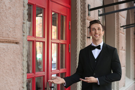 Young doorman in elegant suit standing near restaurant entranceの写真素材