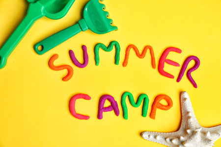 Flat lay composition with words SUMMER CAMP made from modeling clay and beach toys on color backgroundの写真素材