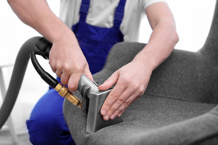 Dry cleaning worker removing dirt from armchair indoorsの写真素材
