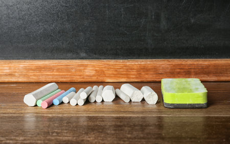 Chalk and duster on table in classroomの写真素材
