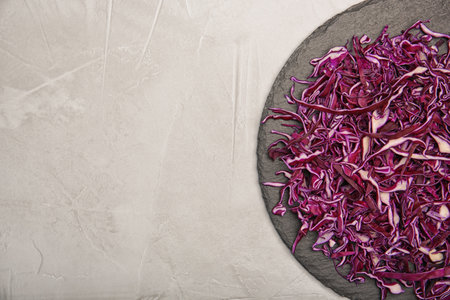Plate with chopped red cabbage on light background, top view