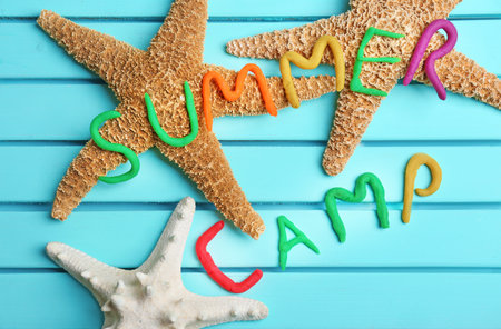 Flat lay composition with words SUMMER CAMP made from modeling clay and sea stars on color backgroundの写真素材