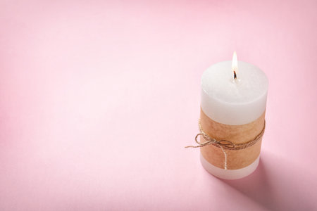 Pillar wax candle burning on color backgroundの写真素材
