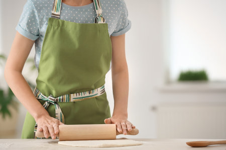 Woman rolling dough at table indoors, closeupの写真素材