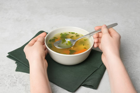 Young woman with bowl of hot broth at table. cold treatmentの写真素材