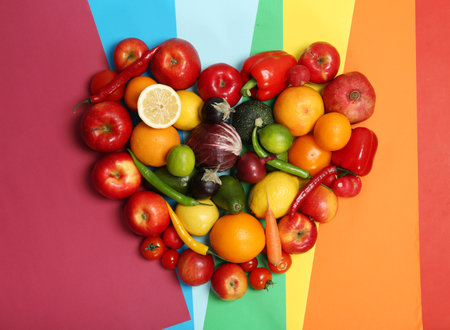 Rainbow heart made of fruits and vegetables on color backgroundの写真素材