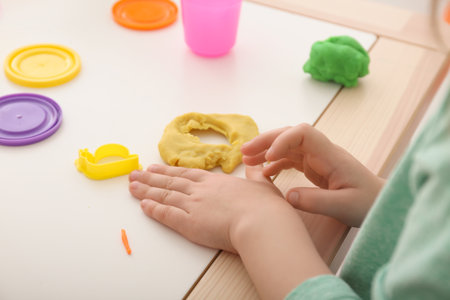 Cute little child using play dough at table, closeupの写真素材