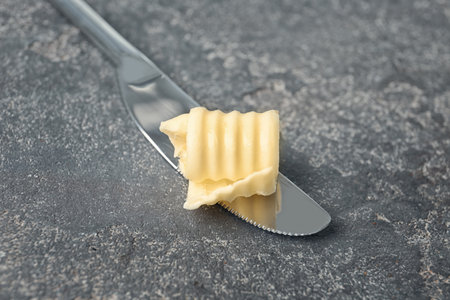 Knife with fresh butter curl on tableの写真素材