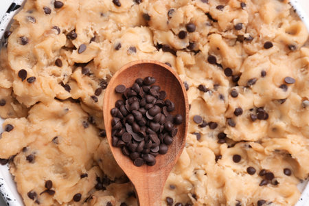 Cookie dough with chocolate chips and wooden spoon, closeupの写真素材