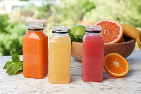 Bottles with tasty juices and ingredients on tableの写真素材