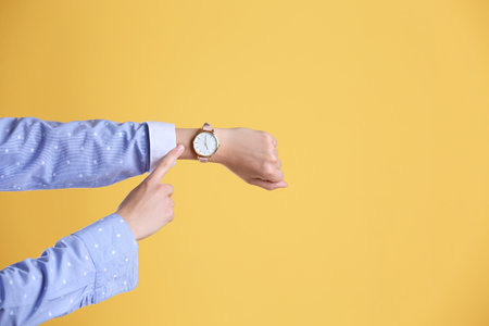 Young woman with wrist watch on color background. time conceptの写真素材