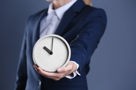 Businesswoman holding alarm clock on color background. time conceptの写真素材