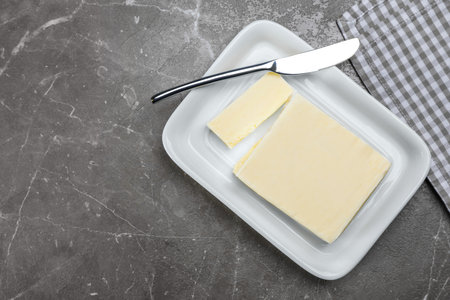 Plate with tasty fresh butter and knife on table, top view