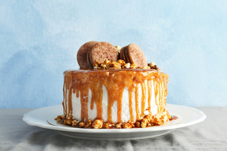Delicious homemade cake with caramel sauce and popcorn on table