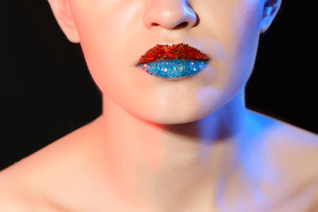 Beautiful young model with creative lips makeup on black backgroundの写真素材