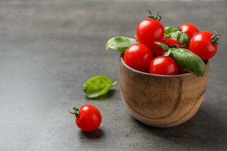 Bowl with ripe red tomatoes and basil on tableの写真素材