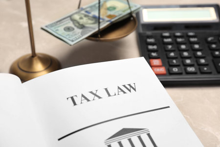 Scales of justice, money and book with words TAX LAW on table, closeupの写真素材