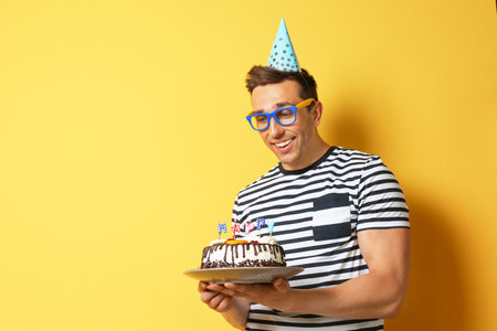 Young man with birthday cake on color backgroundの写真素材