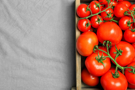 Wooden crate with fresh ripe tomatoes on gray fabricの写真素材