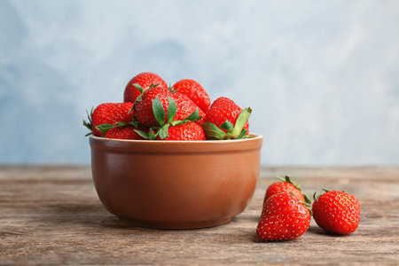 Bowl with ripe red strawberries on wooden tableの写真素材