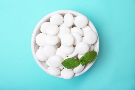 Bowl with tasty mint candies and leaves on color background, top viewの写真素材
