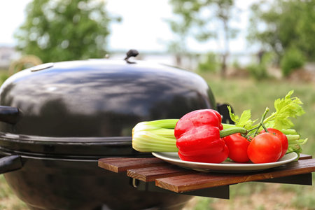 Plate with vegetables near barbecue grill outdoors, closeupの写真素材