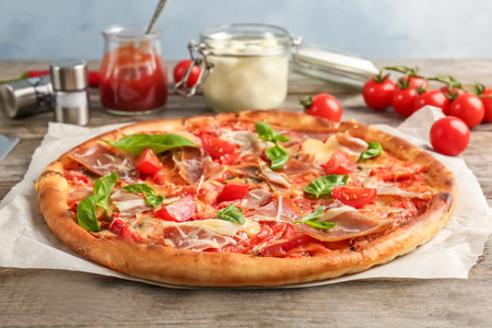 Delicious pizza with tomatoes and meat on tableの写真素材