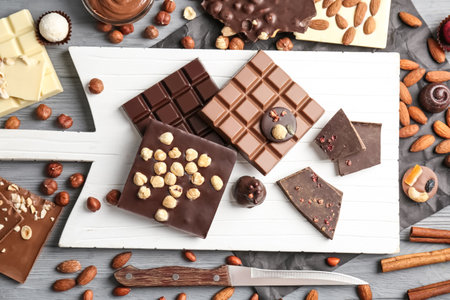 Flat lay composition with different delicious chocolate bars and nuts on tableの写真素材