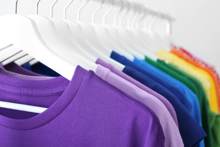 Rack with rainbow clothes on light backgroundの写真素材
