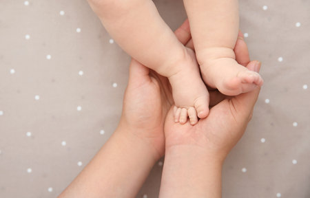 Mother holding little baby feet in hands, top viewの写真素材