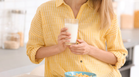Beautiful young woman drinking milk in the kitchenの写真素材