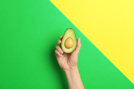 Woman holding ripe cut avocado on color backgroundの写真素材