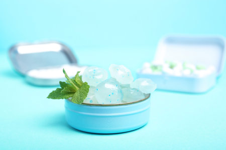 Open box with tasty mint candies and leaves on color background