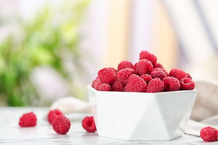 Bowl with ripe aromatic raspberries on tableの写真素材