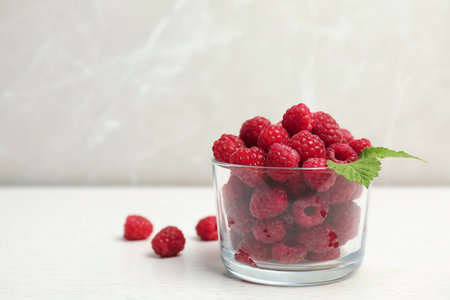 Glass with ripe aromatic raspberries on tableの写真素材