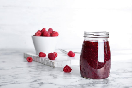 Jar with delicious raspberry jam on tableの写真素材