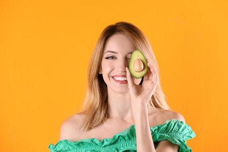 Portrait of young beautiful woman with ripe delicious avocado on color backgroundの写真素材