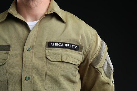 Male security guard in uniform on dark background, closeupの写真素材