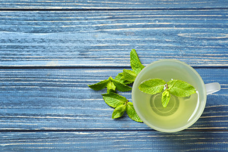 Cup with hot aromatic mint tea and fresh leaves on wooden table, top viewの写真素材