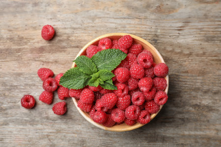 Bowl with ripe aromatic raspberries on wooden table, top viewの写真素材