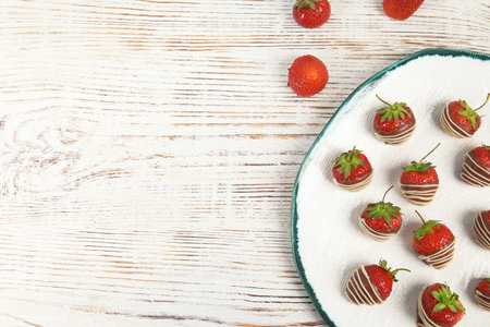 Plate with chocolate covered strawberries on wooden background, top viewの写真素材