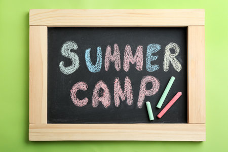 Text "SUMMER CAMP" on small blackboard and colorful chalk, top viewの写真素材