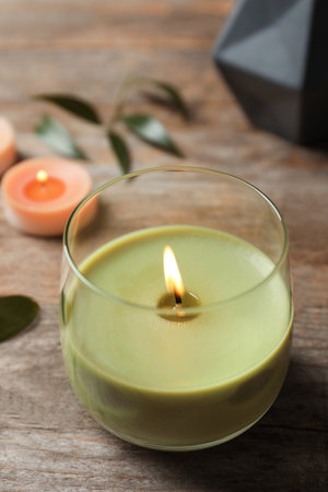 Beautiful burning wax candle on wooden tableの写真素材