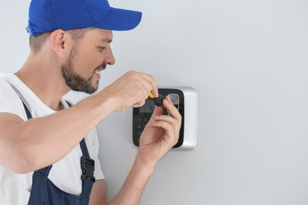 Male technician installing alarm system indoors