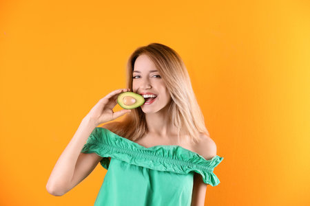 Portrait of young beautiful woman with ripe delicious avocado on color backgroundの写真素材