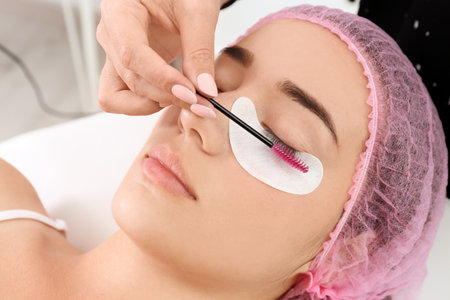 Young woman undergoing eyelash extensions procedure, closeup