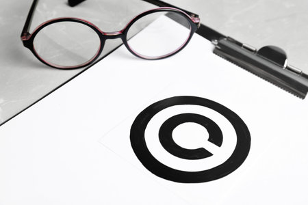 Clipboard with copyright symbol and glasses on table, closeup. Law compliance concept